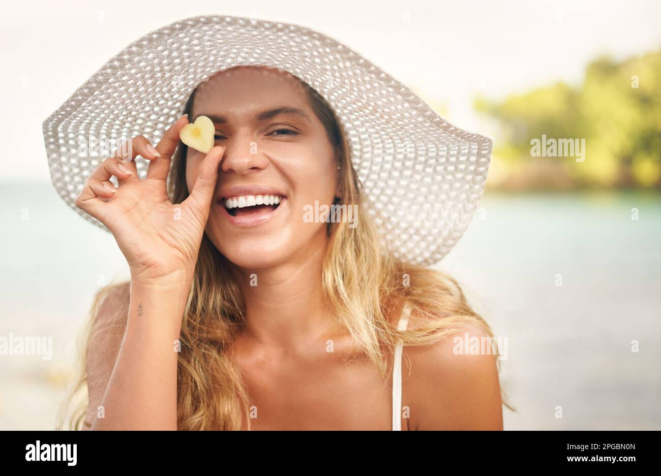 Profiter de toutes mes vacances. Portrait court d'une jeune femme attrayante debout et jouée d'un morceau d'ananas en forme de cœur Banque D'Images