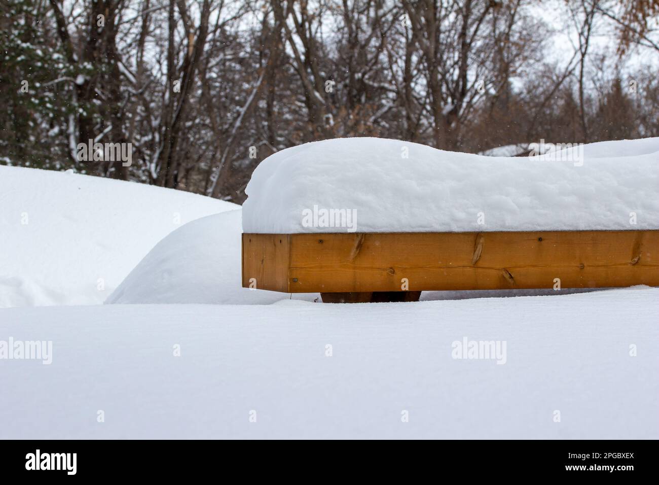Vue abstraite au niveau du sol d'une terrasse et d'un banc en bois, couverts de neige épaisse après un blizzard Banque D'Images
