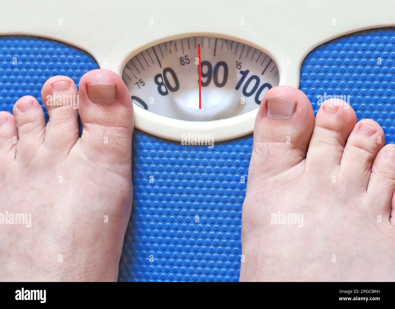 Gros plan des pieds d'homme pesant dans la salle de bains, les pieds d'homme debout sur une balance Banque D'Images