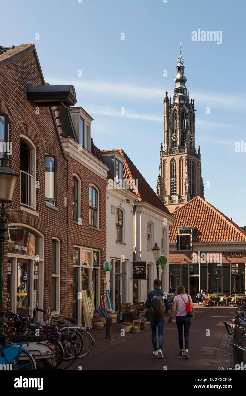 Jeune couple marche main dans la main à travers une rue étroite confortable à travers le centre d'Amersfoort. Banque D'Images