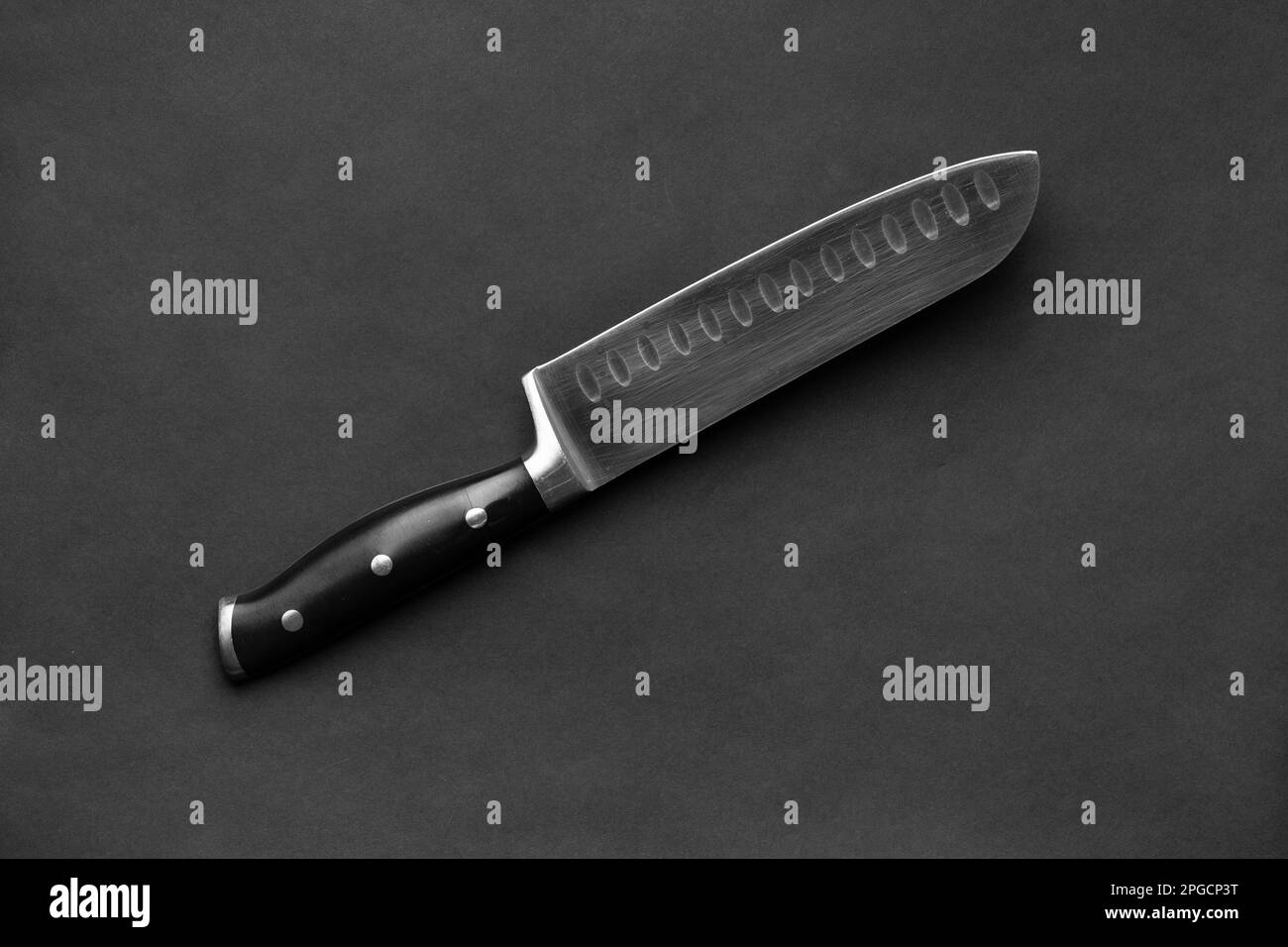 Couteau de cuisine avec poignée noire sur fond noir. Grand couteau sur fond sombre. Ustensiles de cuisine. Couteau à lame large. Banque D'Images