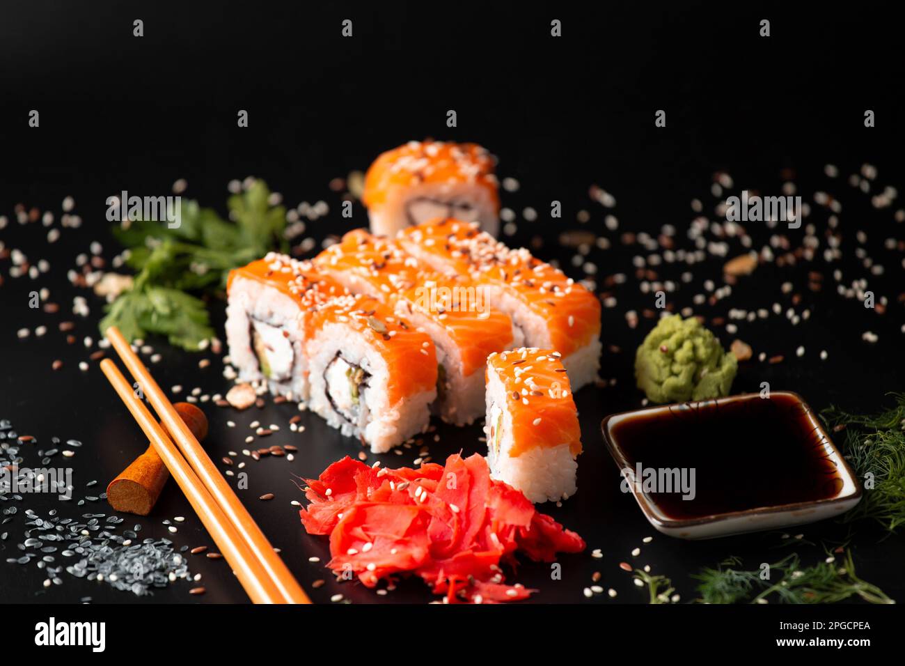 La gamme de différents types de sushis et de petits pains japonais. Sur fond rustique foncé. Roule sur un arrière-plan sombre. Ensemble de fruits de mer avec baguettes. Usefu Banque D'Images