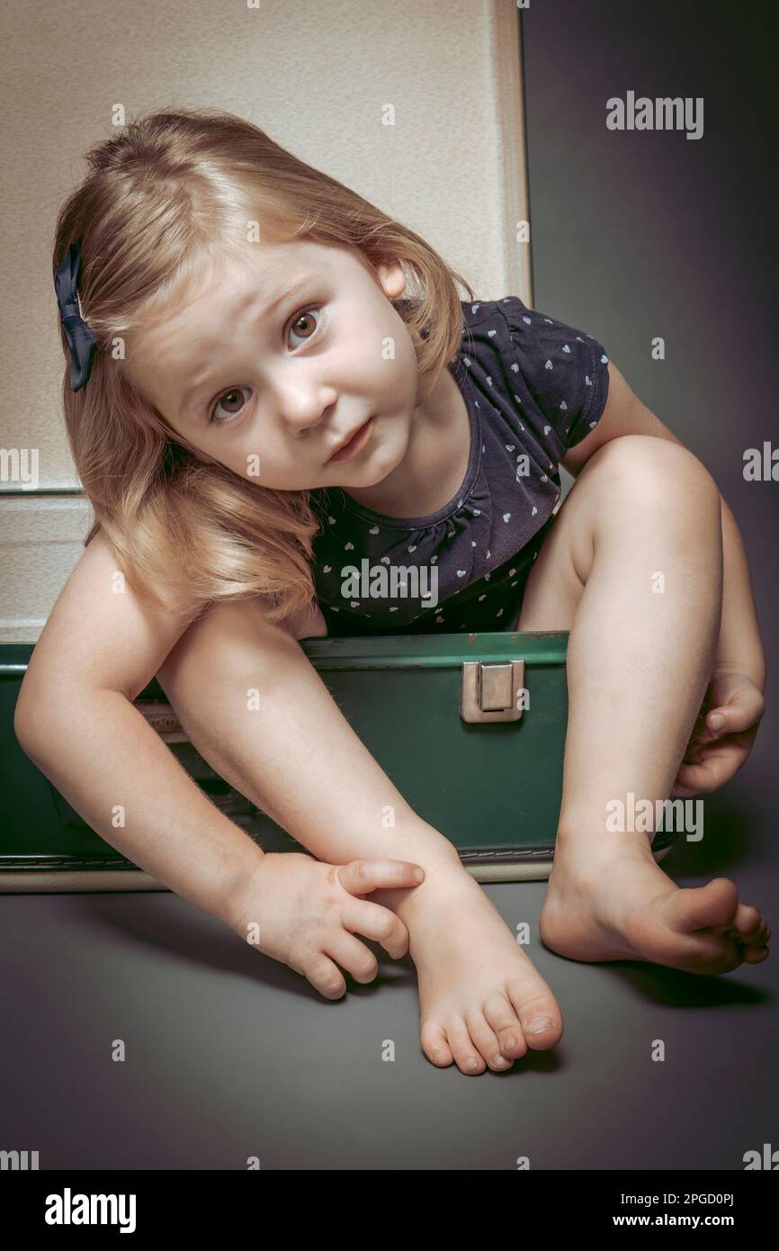 portrait d'une fille blonde à l'intérieur d'une vieille valise Banque D'Images