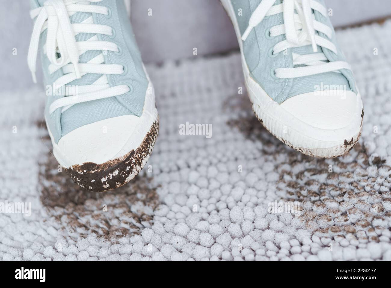 Une paire de baskets sales sur le fond avec une empreinte sur un tapis gris propre à l'intérieur. Chaussures sales avec de la boue et du sol Banque D'Images
