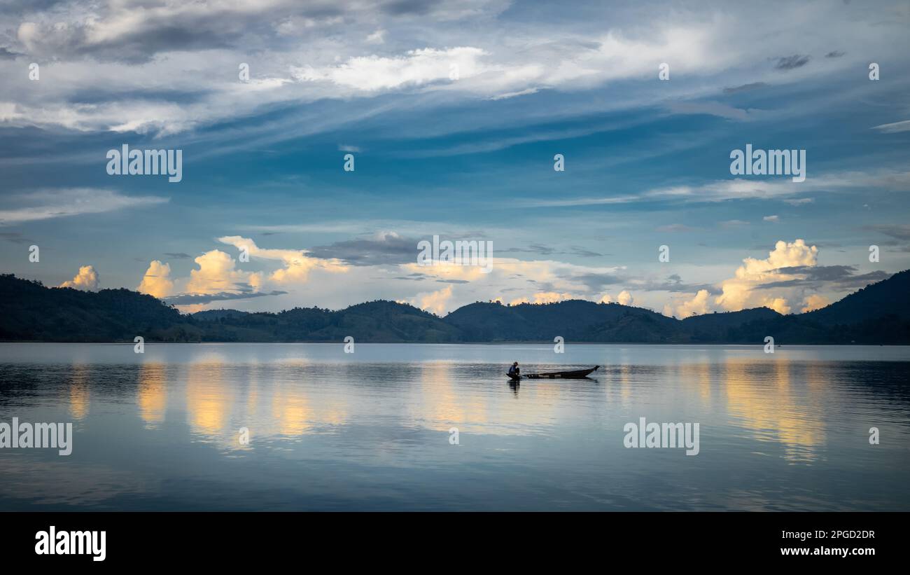 Un homme minoritaire ethnique Mnong isolé sur son canot en bois part pêcher sur le lac Lak à Buon Jun à lien son, Vietnam. Banque D'Images