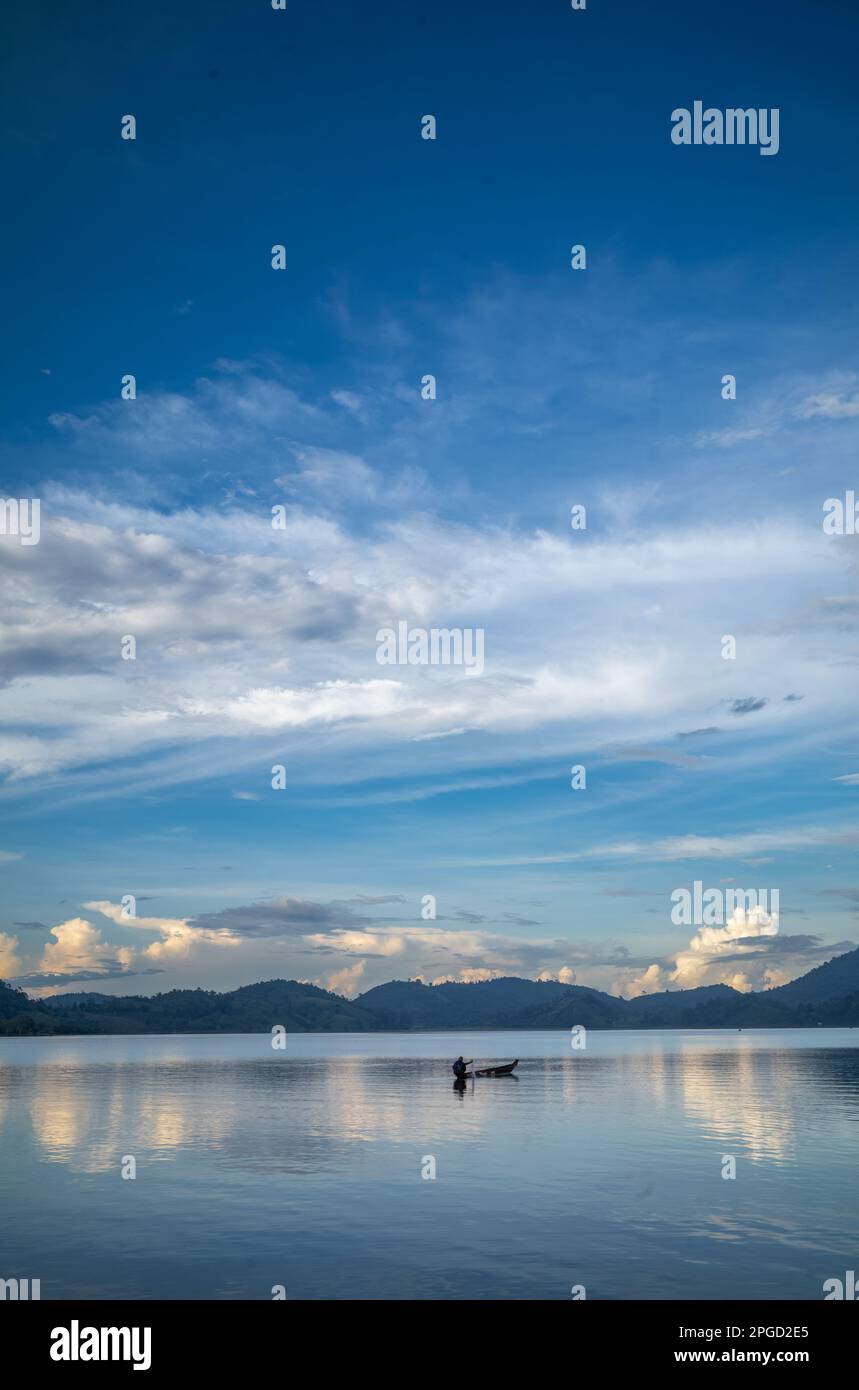 Un homme minoritaire ethnique Mnong isolé sur son canot en bois part pêcher sur le lac Lak à Buon Jun à lien son, Vietnam. Banque D'Images