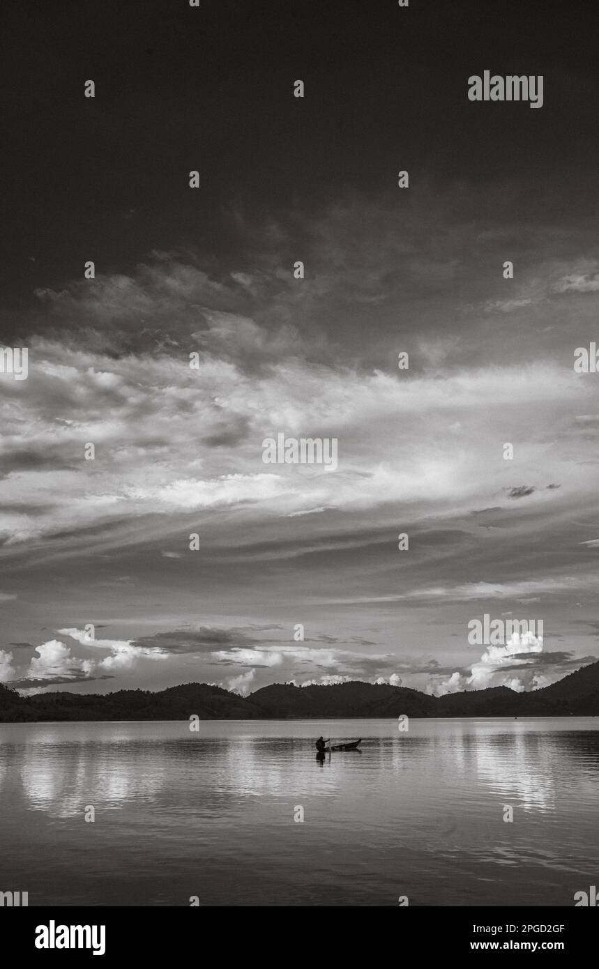 Un homme minoritaire ethnique Mnong isolé sur son canot en bois part pêcher sur le lac Lak à Buon Jun à lien son, Vietnam. Banque D'Images