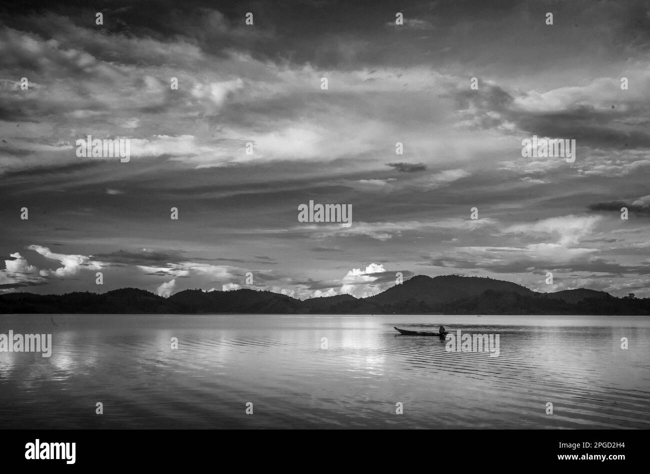 Un homme minoritaire ethnique Mnong isolé sur son canot en bois part pêcher sur le lac Lak à Buon Jun à lien son, Vietnam. Banque D'Images