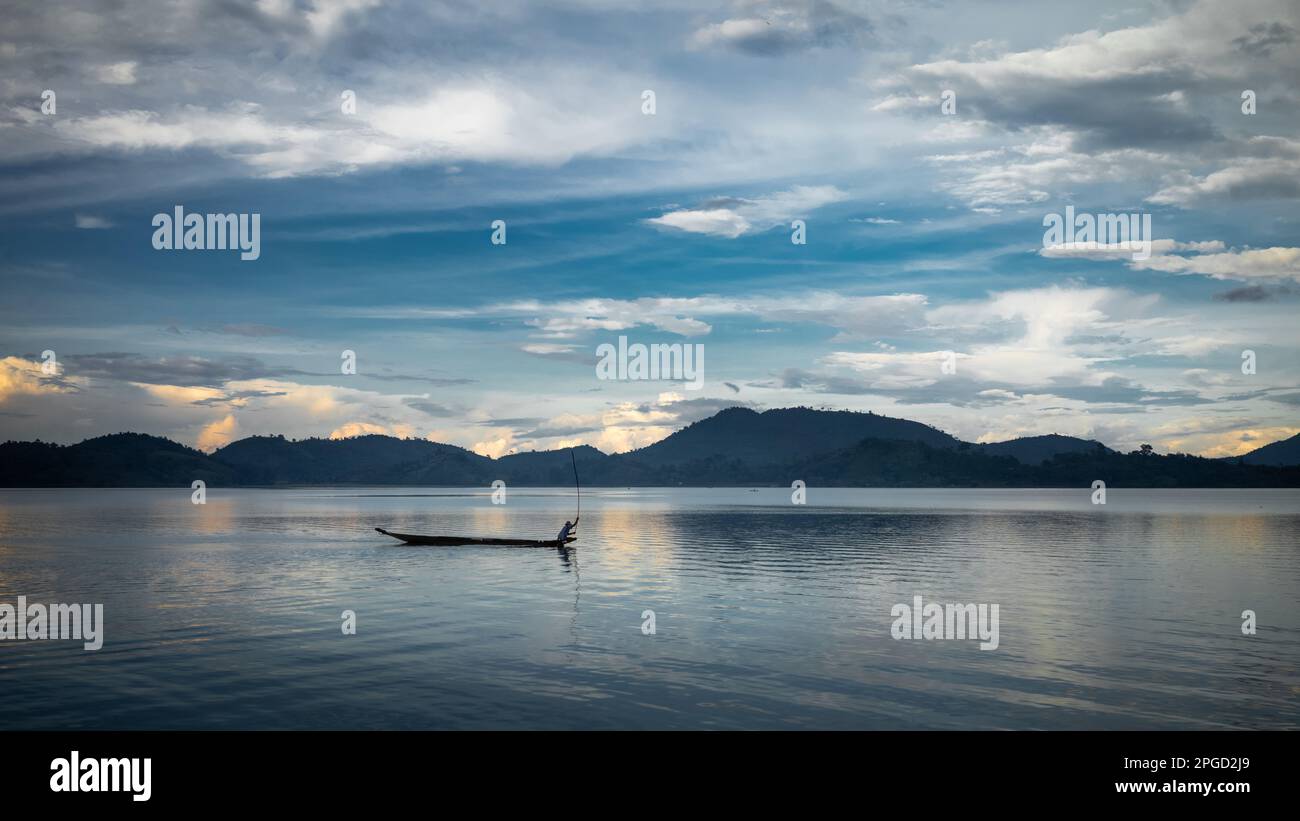 Un homme minoritaire ethnique Mnong isolé sur son canot en bois jette sa canne à pêche dans le lac Lak à Buon Jun, à lien son, au Vietnam. Banque D'Images