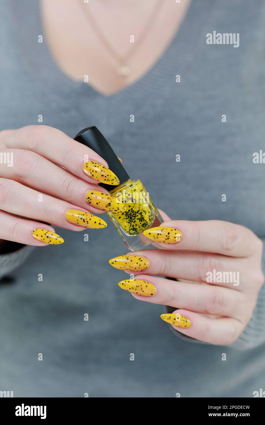 Belle main femelle avec de longs ongles et un vernis à ongles jaune et noir  Photo Stock - Alamy