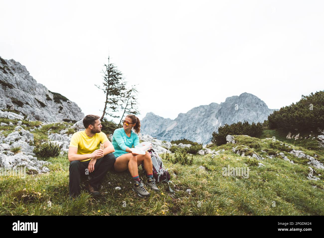 Couple d'alpinisme assis sur l'herbe ayant une pause de la randonnée un beau sentier dans les Alpes d'été Banque D'Images