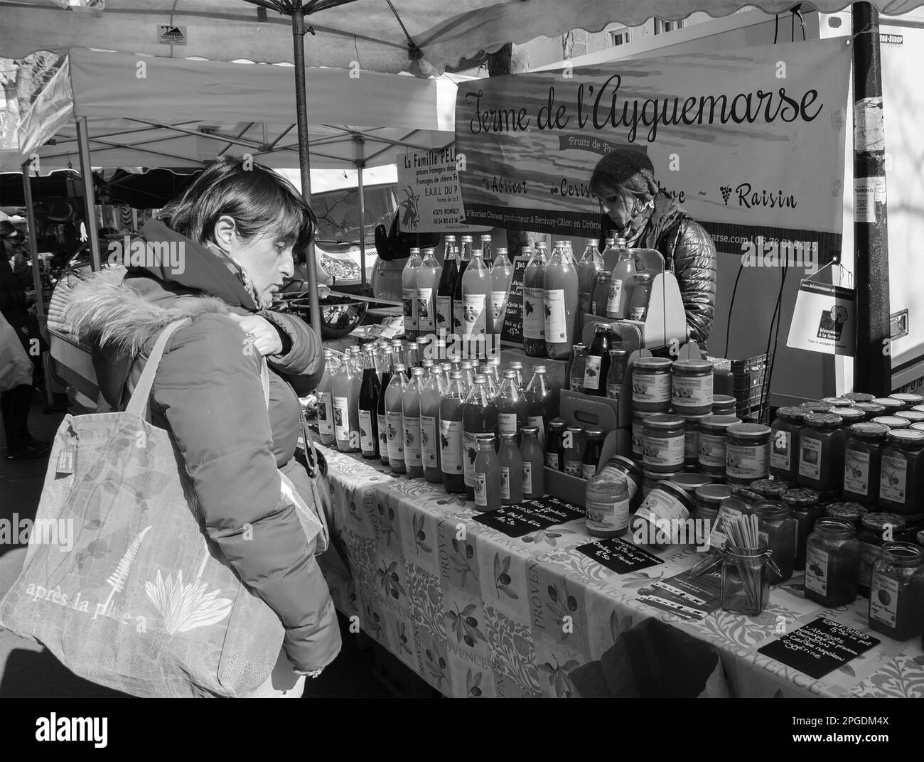 Paris, France - 12 mars 2016 : une femme choisit de la confiture et du jus au marché agricole local de Paris. Photo historique noir et blanc Banque D'Images