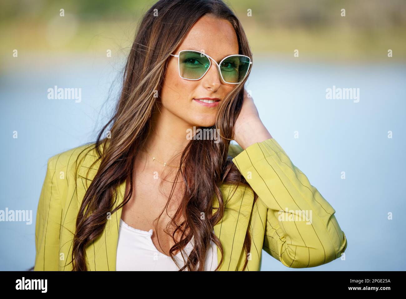 Jeune modèle féminin en mode rétro posé dans des lunettes de soleil teintées vertes Banque D'Images