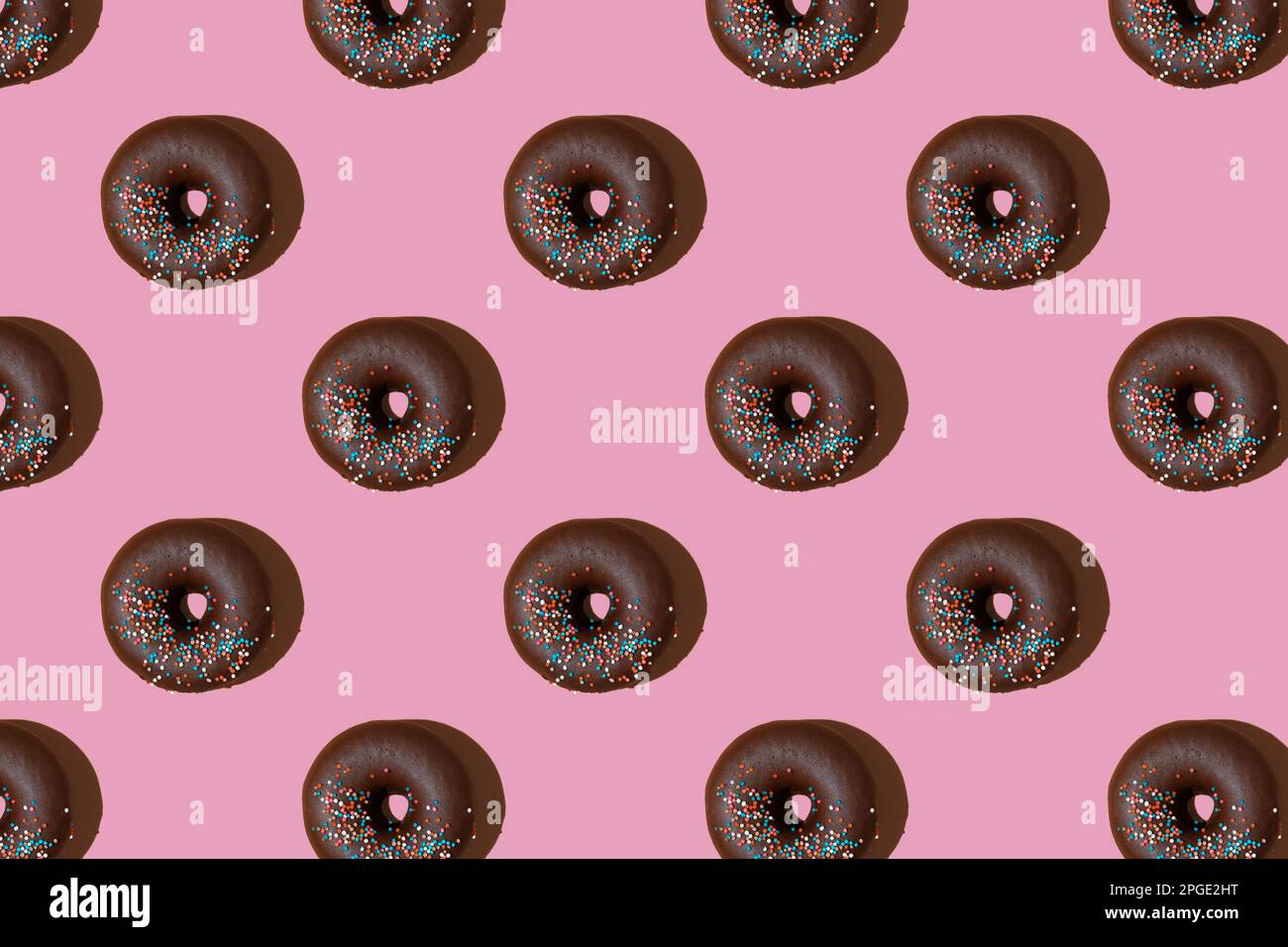 Motif de beignets de chocolat isolé sur fond rose. Boulangerie, beignet, gâteries, aliments sucrés. Vue de dessus, plat, papier peint, toile de fond Banque D'Images