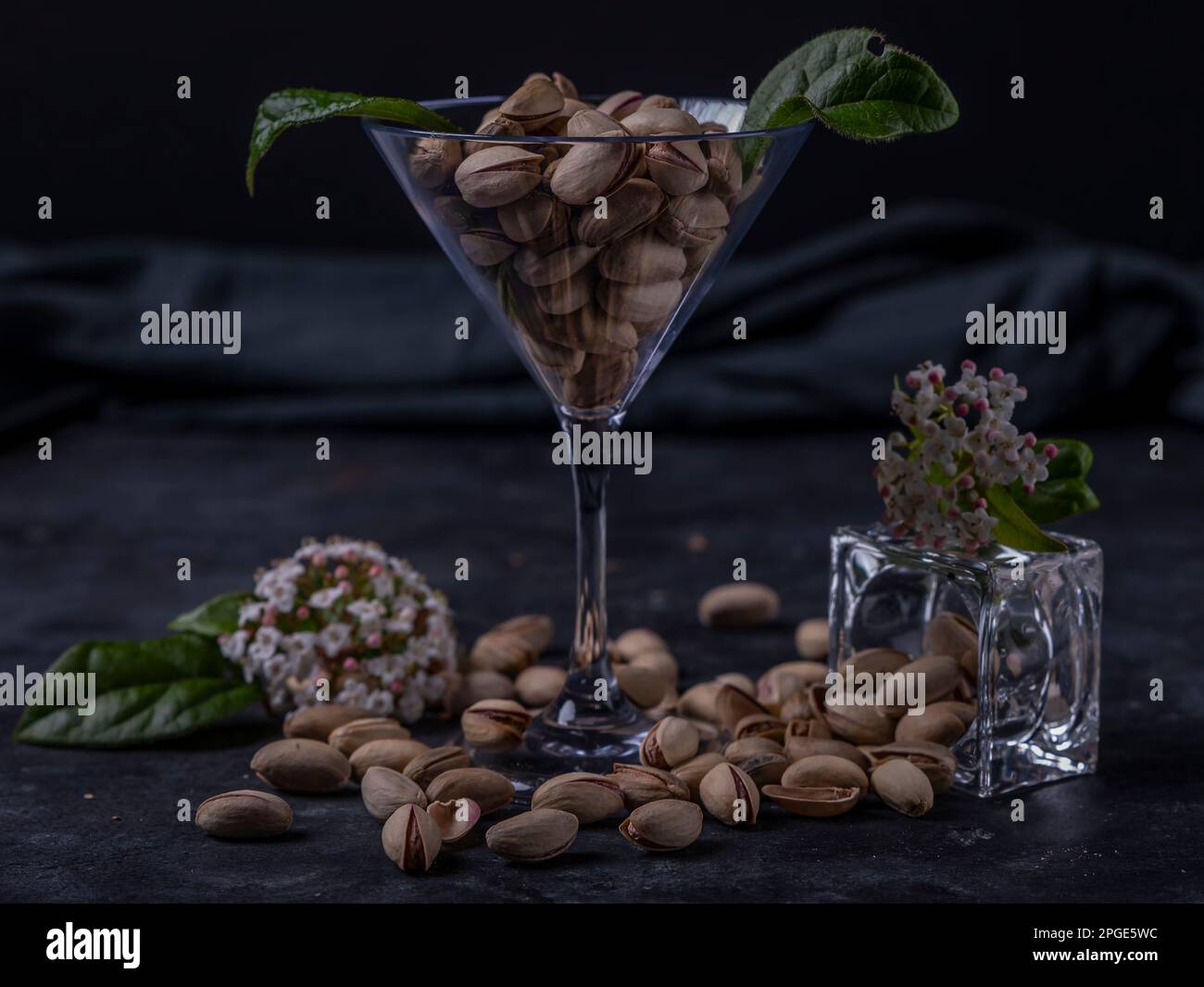 Les pistaches sont contenues dans un verre transparent et placées sur la table, avec des fleurs printanières Banque D'Images