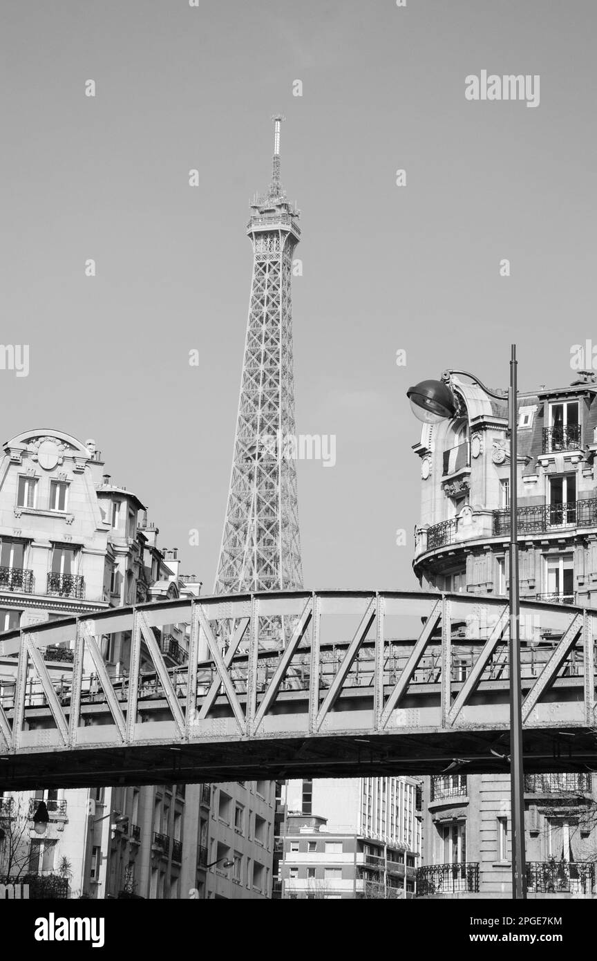 Paysage urbain de Paris avec pont de métro (avec train de passage), tour Eiffel et drapeau français accrochés par la fenêtre d'un bâtiment typiquement parisien. Noir blanc Banque D'Images