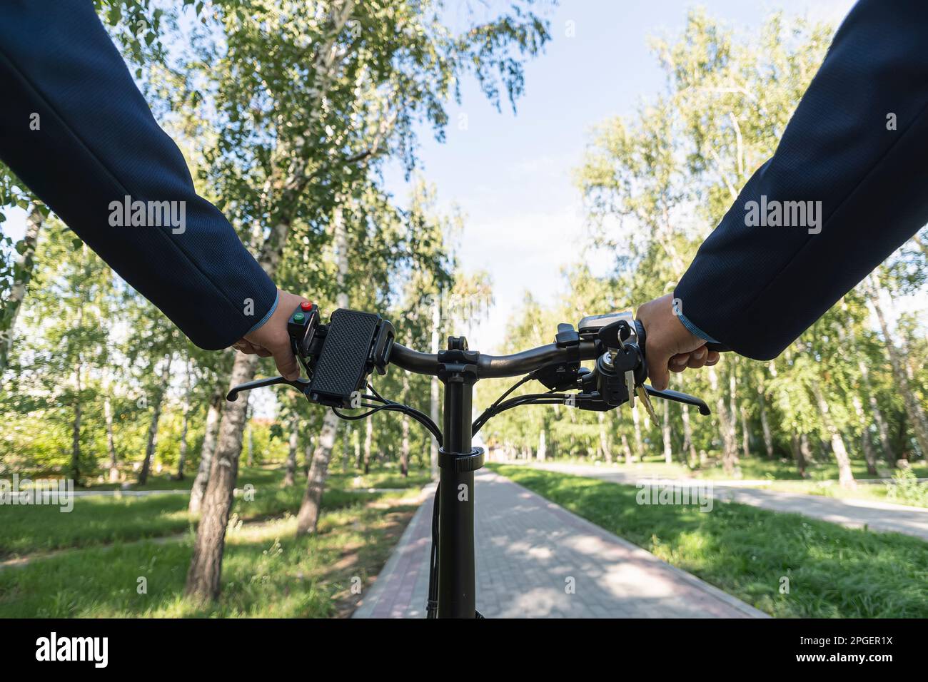 Vue depuis les yeux des motards. Gros plan de cycliste homme mains sur guidon vélo électrique dans le parc, le visage n'est pas visible.Jeune homme vélo dans la cour Banque D'Images