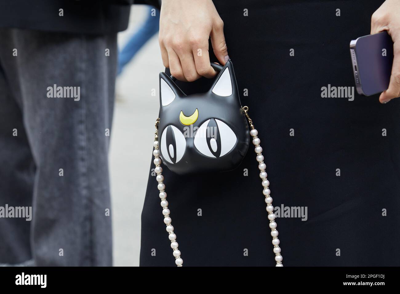 MILAN, ITALIE - 24 FÉVRIER 2023: Femme avec robe noire et sac avec chat et demi-lune avec bracelet perles avant Sportmax défilé de mode, Milan Fashion Banque D'Images