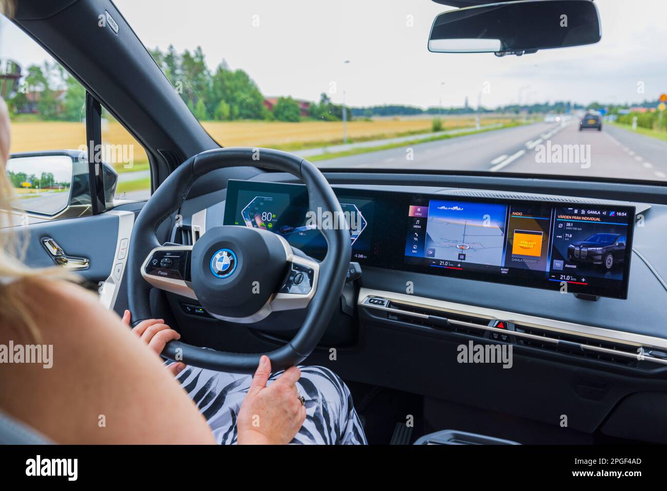 Vue rapprochée de l'intérieur de la BMW iX 40 sur route. Une femme conduit un véhicule sur la voie publique. Suède. Banque D'Images