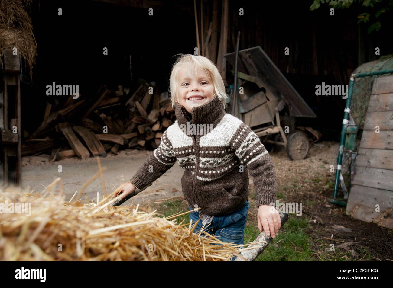 Portrait d'un petit garçon poussant la brouette dans la ferme, Bavière, Allemagne Banque D'Images