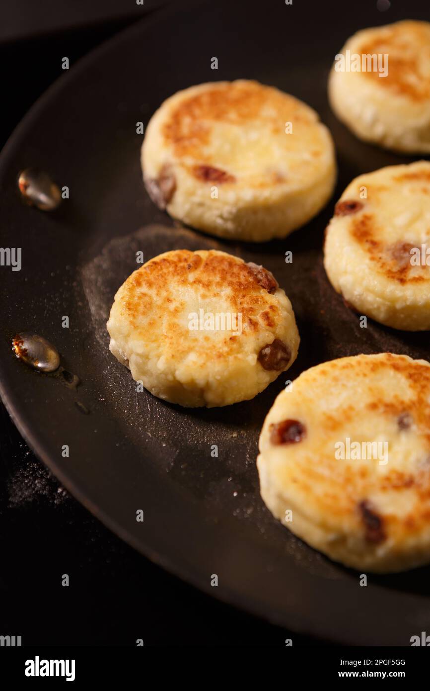 Délicieux syrniki ukrainien cuisiné dans une cuisine. Gâteaux au fromage doux friture sur une poêle chaude. Dessert d'Ukraine Banque D'Images