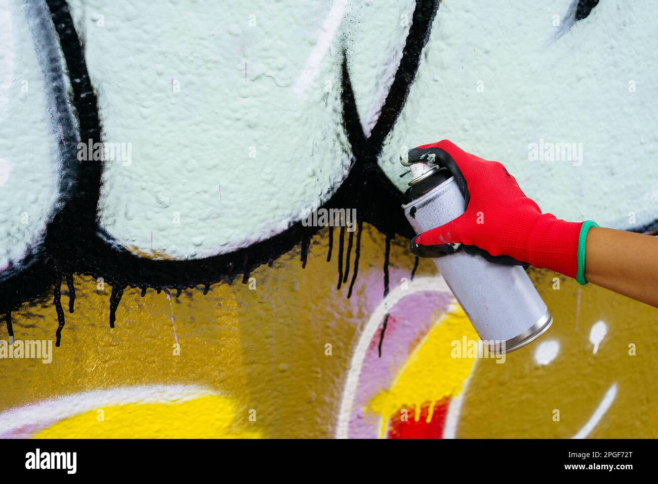 Main humaine dans le gant rouge dessinant des graffitis sur le mur Banque D'Images