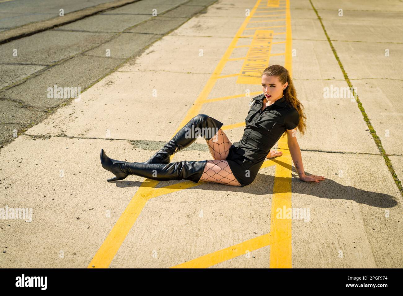 Jeune femme en Goth tenue assise sur une allée en béton Banque D'Images