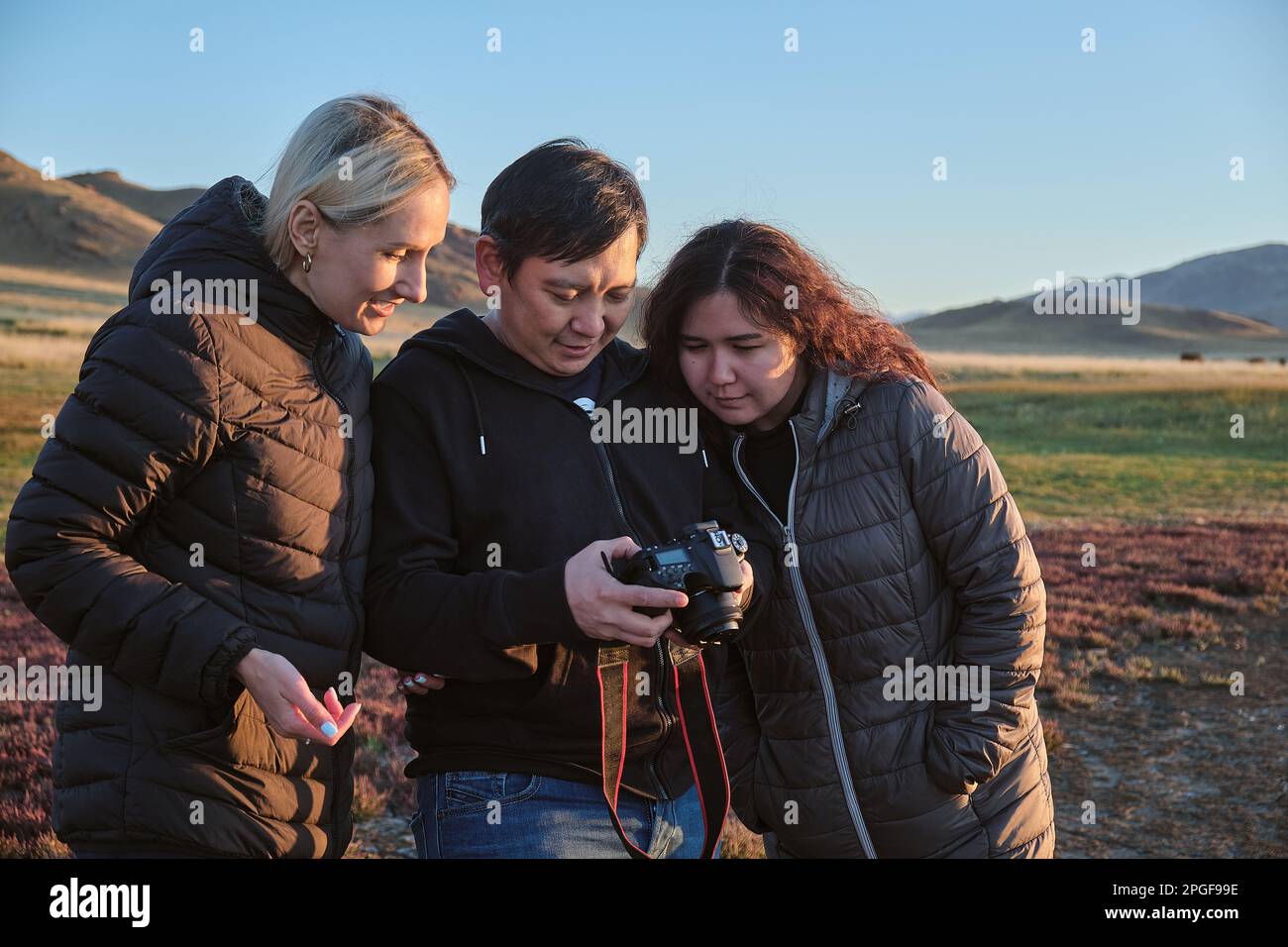Guy et deux femmes, amis, regardant des photos sur l'écran de l'appareil photo Banque D'Images