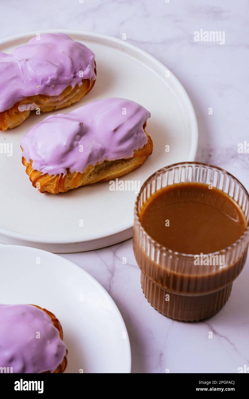 eclair dans un glaçage aux baies violettes et café avec du lait dans un  verre Photo Stock - Alamy