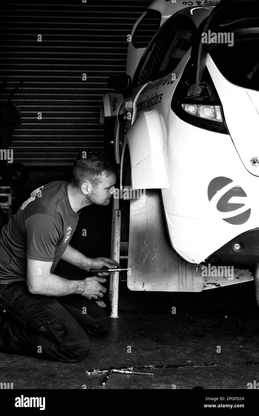 Image en noir et blanc d'un mécanicien qui réparse une voiture de rallye Banque D'Images