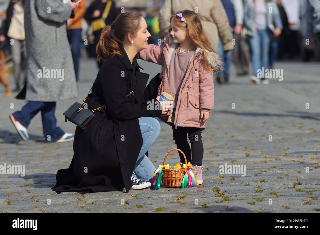 Jeune mère avec sa petite fille au marché de Pâques à Prague, un panier acheté avec des décorations de Pâques sur le grund. Jour de printemps ensoleillé, pas d'ai Banque D'Images