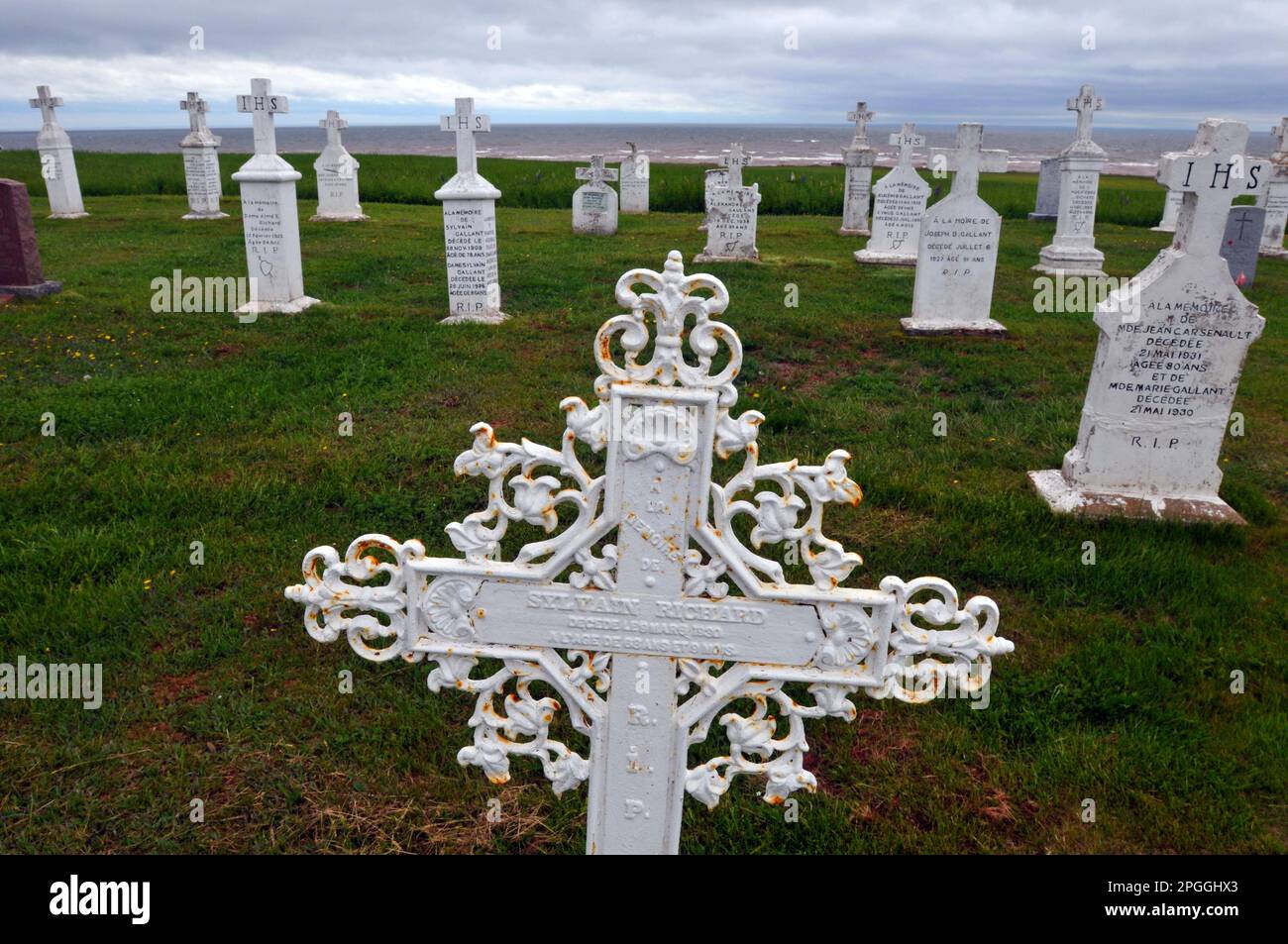 Une croix en métal ornée marque une tombe dans le cimetière en bord de mer de l'église notre Dame du Mont Carmel à Mont Carmel, Île-du-Prince-Édouard. Banque D'Images