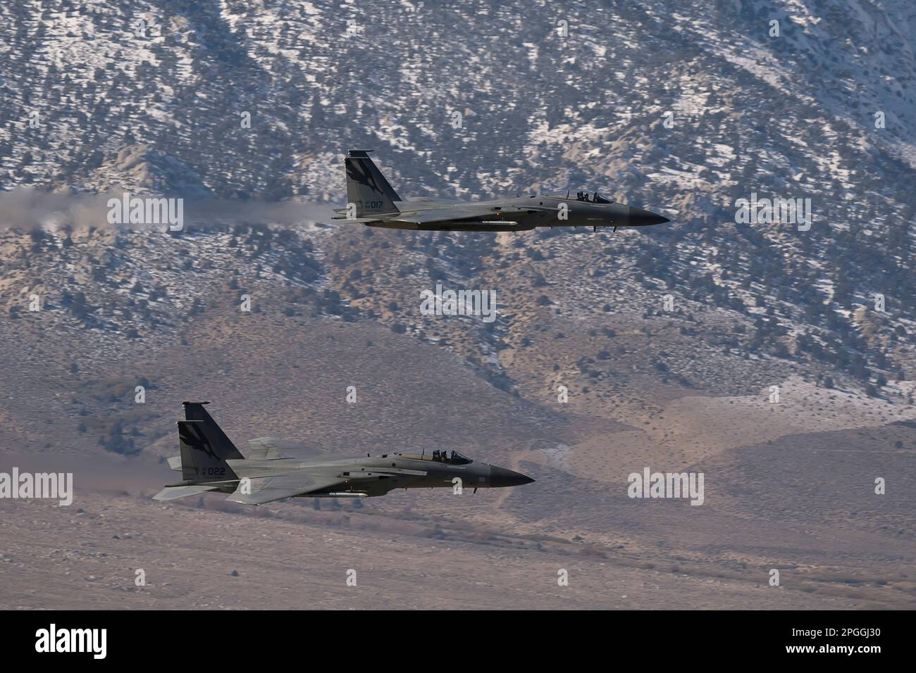 Lone Pine, CA - 10 novembre 2022 : deux chasseurs F-15 de l'USAF volent au niveau inférieur sur le sentier de bas niveau Sidewinder-D avec des montagnes enneigées dans le b Banque D'Images