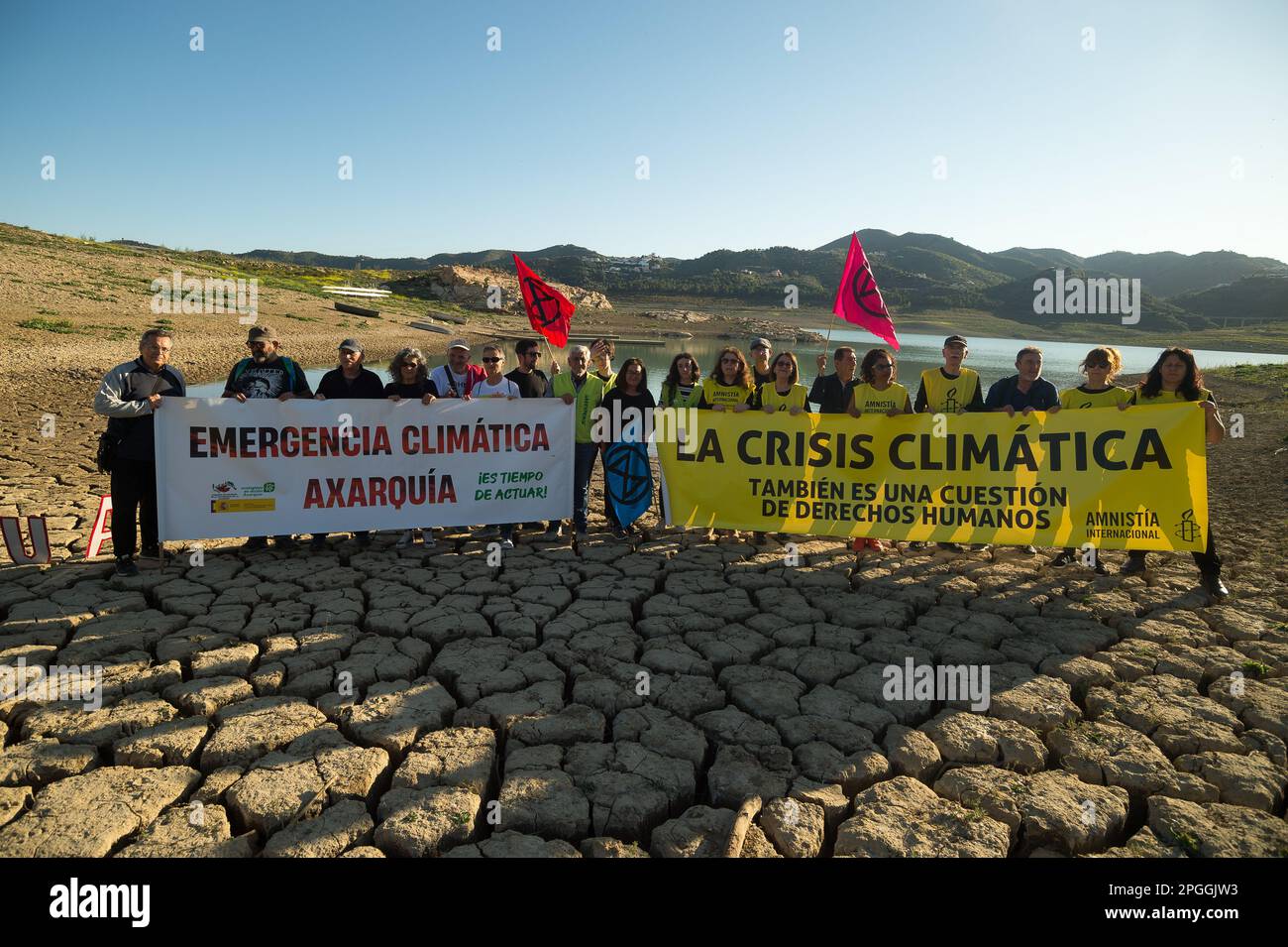 Les militants de l'environnement et des droits de l'homme sont vus brandissant de grandes banderoles sur les terres fissurées lors d'une manifestation contre le changement climatique, organisée par Amnesty International. Pour marquer la Journée internationale de l'eau, des militants d'Amnesty International, ainsi que plusieurs organisations environnementales, ont dénoncé le changement climatique et ses effets sur les droits de l'homme dans le monde entier par une performance qui représente la mort symbolique du réservoir de la Viñuela. Le réservoir de Viñuela, qui fournit de l'eau aux municipalités situées près de la région d'Axarquia, est à un niveau d'eau minimal dû à Banque D'Images