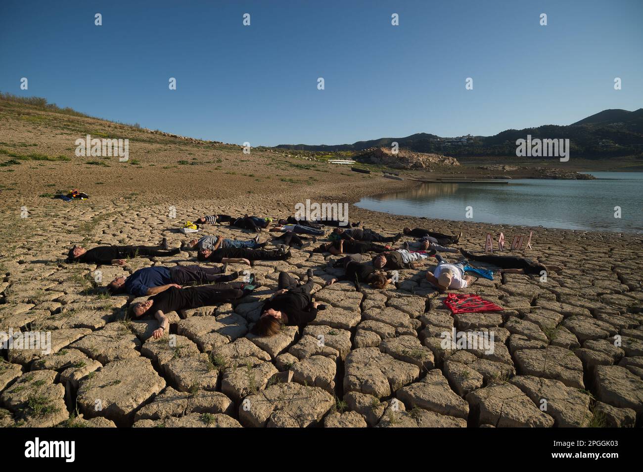 Les militants des droits de l'homme et de l'environnement sont vus sur un terrain fissuré lors d'une manifestation contre le changement climatique, organisée par Amnesty International. Pour marquer la Journée internationale de l'eau, des militants d'Amnesty International, ainsi que plusieurs organisations environnementales, ont dénoncé le changement climatique et ses effets sur les droits de l'homme dans le monde entier par une performance qui représente la mort symbolique du réservoir de la Viñuela. Le réservoir de Viñuela, qui fournit de l'eau aux municipalités près de la région d'Axarquia, est à un niveau d'eau minimal en raison de la grave sécheresse dans la province. (Photo Banque D'Images