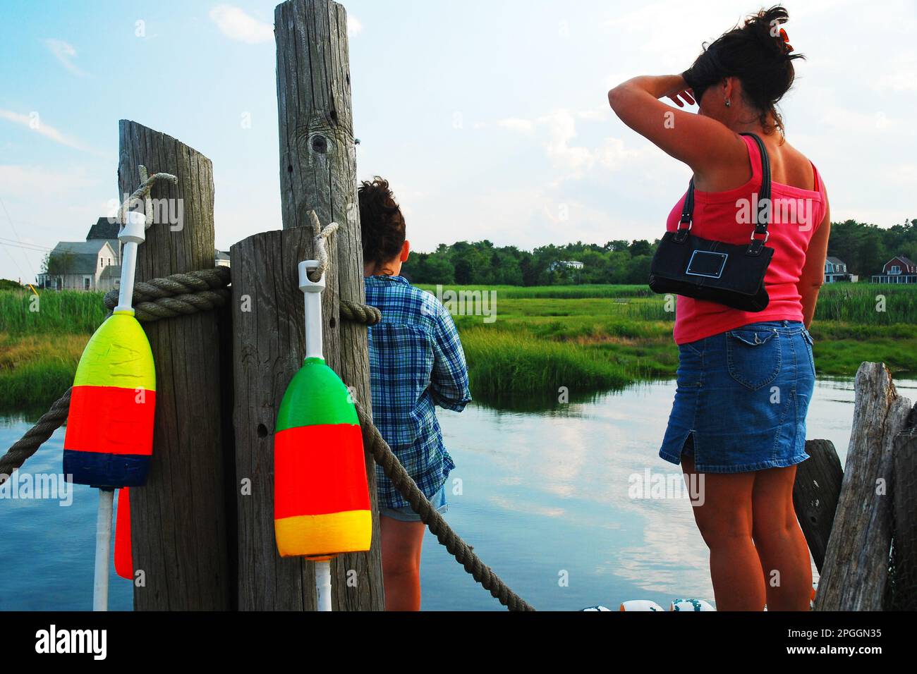 Une mère et un fils se tiennent sur un quai et une jetée de la Nouvelle-Angleterre et regardent sur l'eau un jour d'été Banque D'Images
