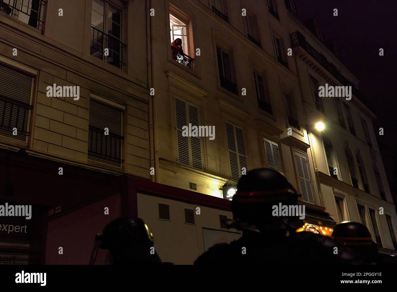 Une femme observe la situation depuis la fenêtre. Un groupe de Parisiens proteste dans les rues de la capitale française après la réforme de l'âge de la retraite. Banque D'Images