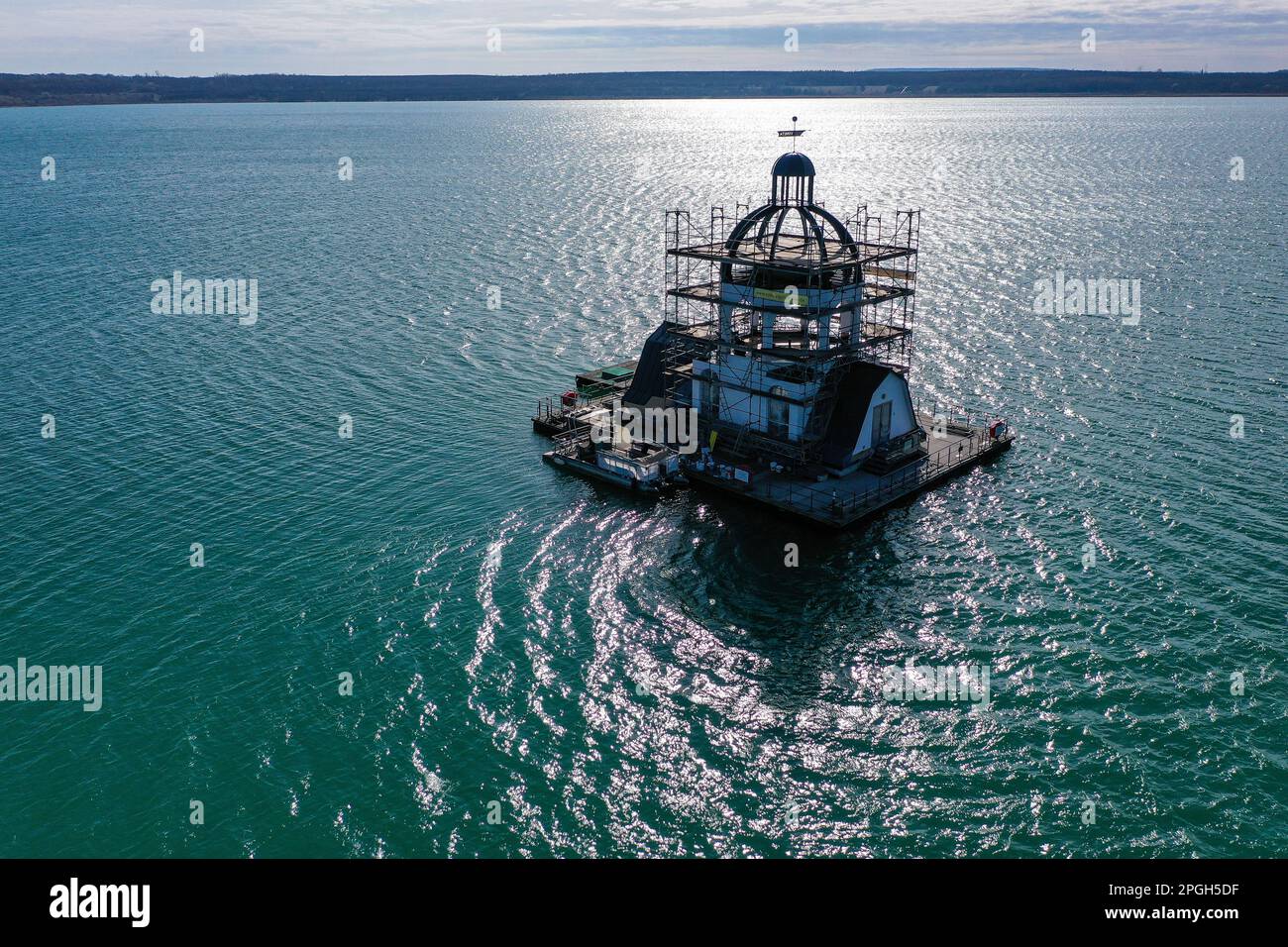 PRODUCTION - 22 mars 2023, Saxe, Großpösna: Vue de l'église flottante en échafaudage 'Vineta' sur le lac Störmthal. Après une bonne décennie sur l'eau et le vent permanent et le temps, la façade doit être renouvelée et peinte. La Vineta n'est pas une église consacrée, mais sa tour de 15 mètres est calquée sur le clocher de l'ancienne église de Magdeborn. Le village de Magdeborn était l'un des nombreux endroits qui ont dû céder la place à l'extraction de lignite à ciel ouvert. Le lac Störmthal a été créé par l'inondation de la mine. Des concerts, des lectures ou des célébrations privées telles que des cérémonies de mariage ont lieu sur la Vineta. (À dpa : « T Banque D'Images