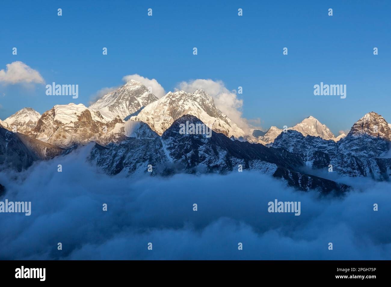 Vue sur l'Everest depuis Gokyo RI. Pittoresque vallée de montagne remplie de nuages mauriques au coucher du soleil. Le pic de neige spectaculaire de l'Everest s'élève au-dessus du fleuve de c Banque D'Images