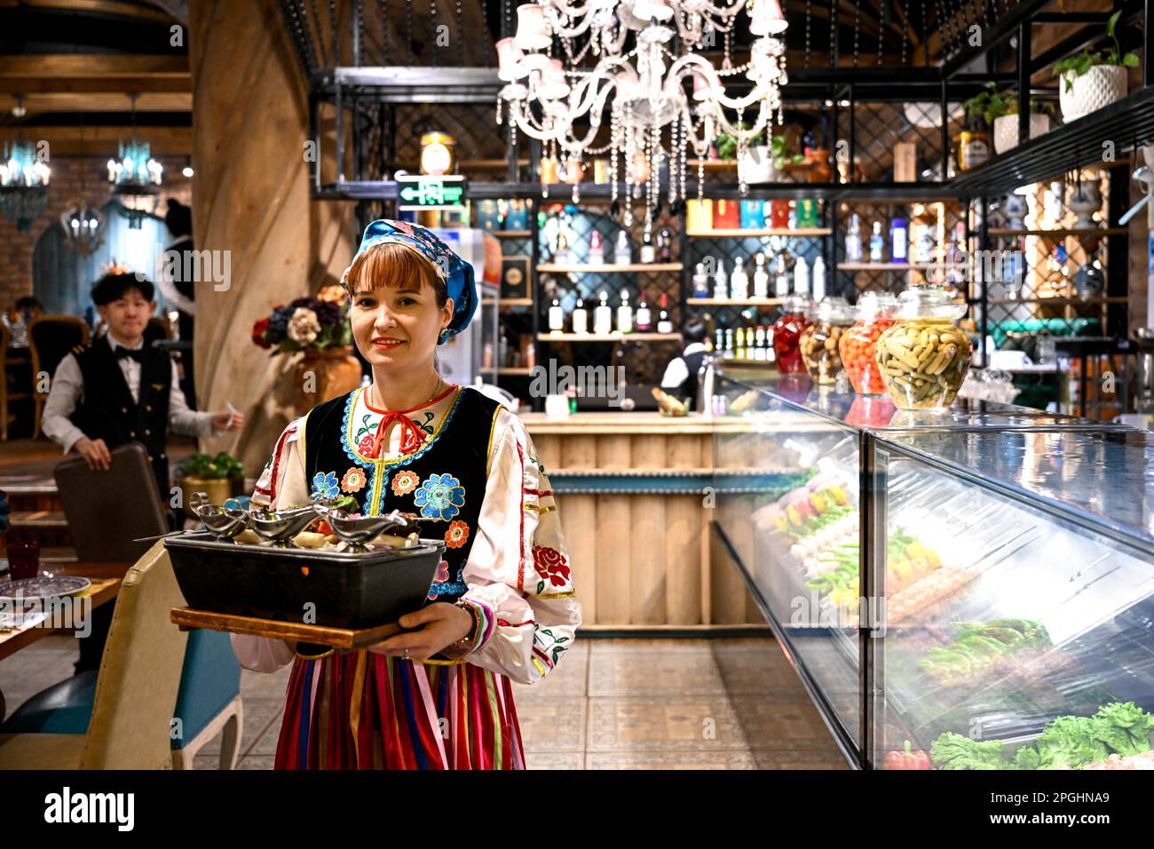 Manzhouli, région autonome de la Mongolie intérieure de la Chine. 15th mars 2023. Une serveuse russe sert de la nourriture dans un restaurant russe à Manzhouli, dans la région autonome de Mongolie intérieure, au nord de la Chine, à 15 mars 2023. La popularité des produits et des aliments russes a repris chez les clients locaux après la reprise des services du port terrestre de Manzhouli. Credit: BEI HE/Xinhua/Alay Live News Banque D'Images