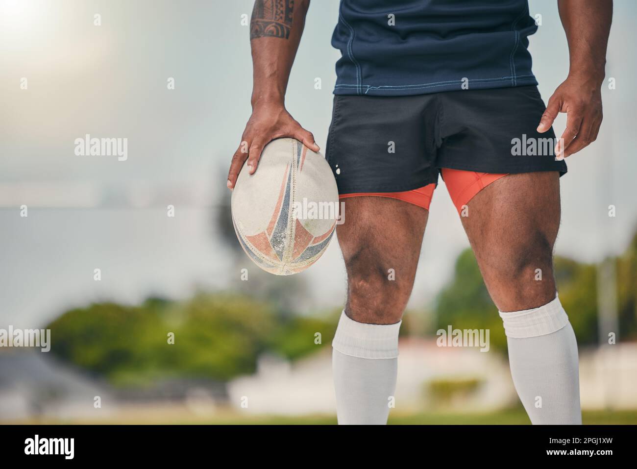 Rugby, homme et ballon, zoom sur les jambes de l'homme fort, musclé prêt à gagner le jeu sur le terrain. Fitness, sport et joueur de sport professionnel à l'entraînement Banque D'Images