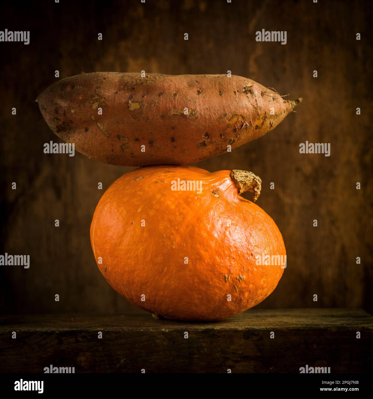 Patate douce et citrouille empilées sur une surface en bois dans un éclairage doux Banque D'Images