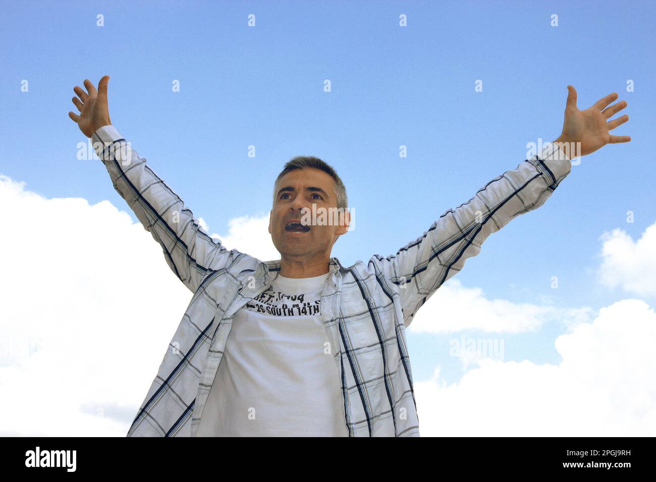homme levant ses bras dans l'air en jubilation, vue de face Banque D'Images