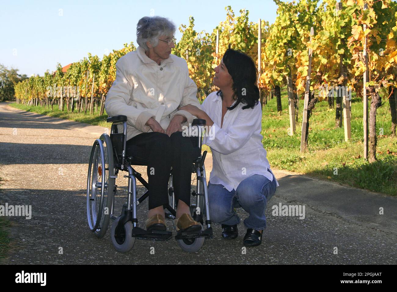 femme parent allaitant une vieille femme en fauteuil roulant pendant une promenade Banque D'Images