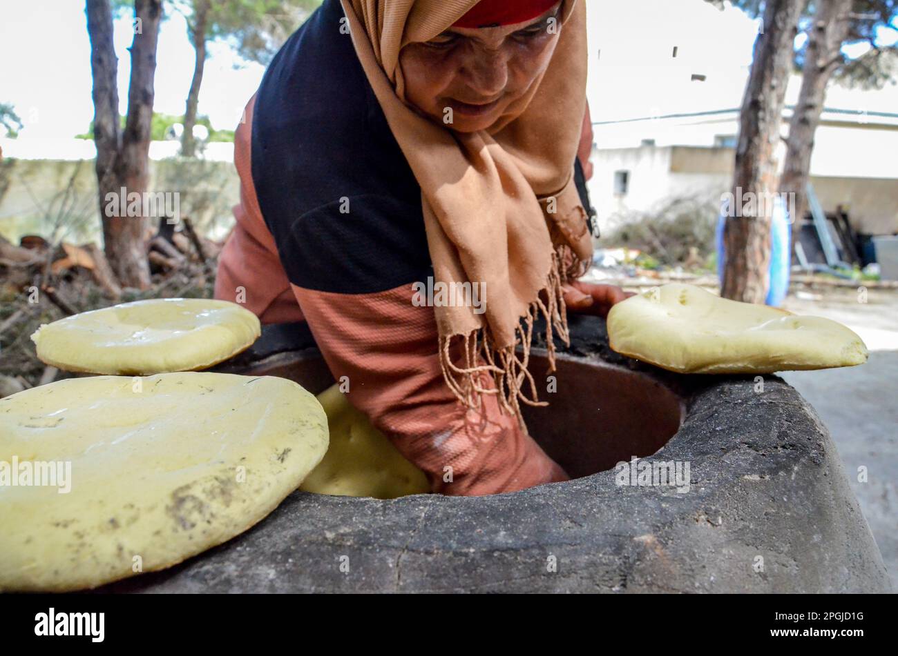 Tunis, Tunisie. 22nd mars 2023. Tunis, Tunisie, 22 mars 2023. Une Tunisienne se fait cuire le pain Tabouna dans un four traditionnel en argile, avant du vendre sur un marché de Tunis. Tabouna est un ancien pain tunisien fait avec du blé, de la semoule ou de la farine d'orge et cuit sur les murs d'un four traditionnel en terre cuite. Tabouna est particulièrement populaire pendant le mois sacré musulman du Ramadan (Credit image: © Hasan mrad/IMAGESLIVE via ZUMA Press Wire) USAGE ÉDITORIAL SEULEMENT! Non destiné À un usage commercial ! Banque D'Images