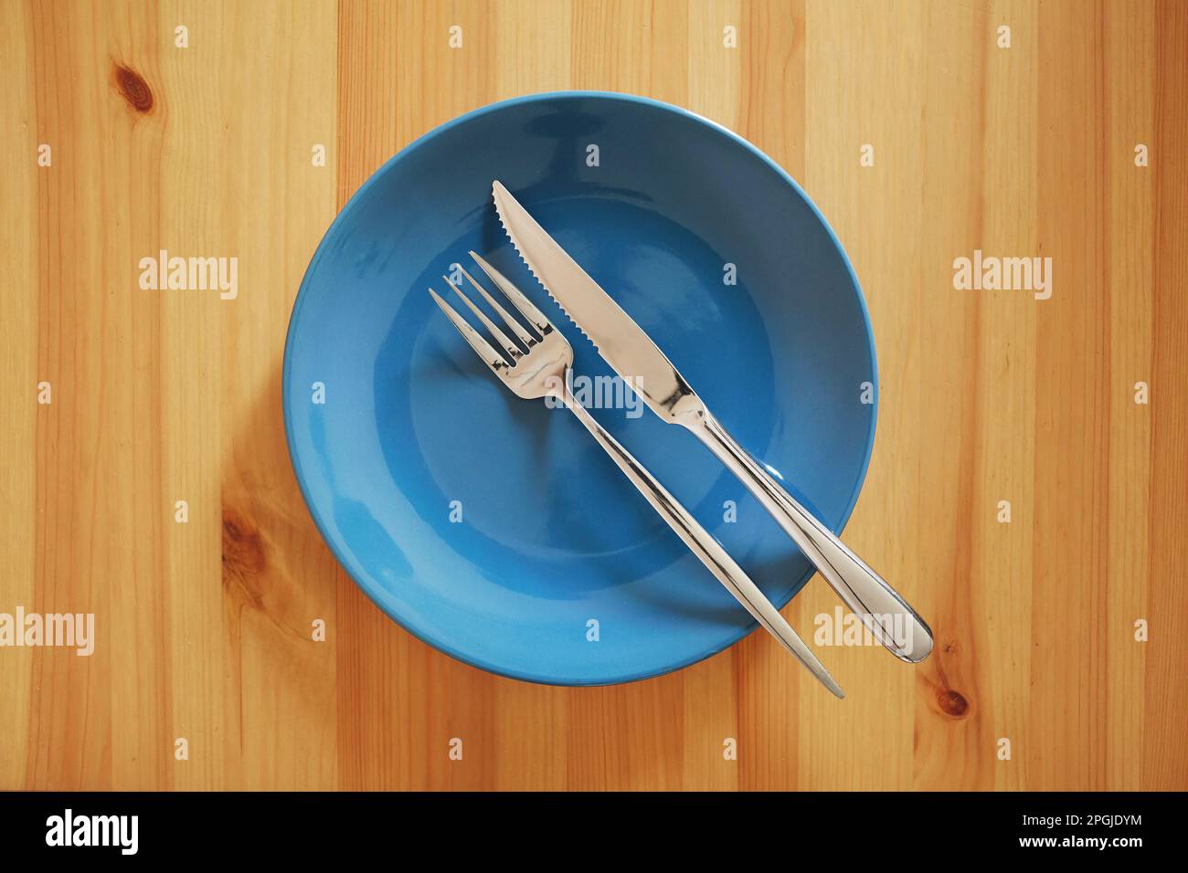 Vider et nettoyer la plaque bleue avec la fourchette et le couteau sur une table en bois Banque D'Images
