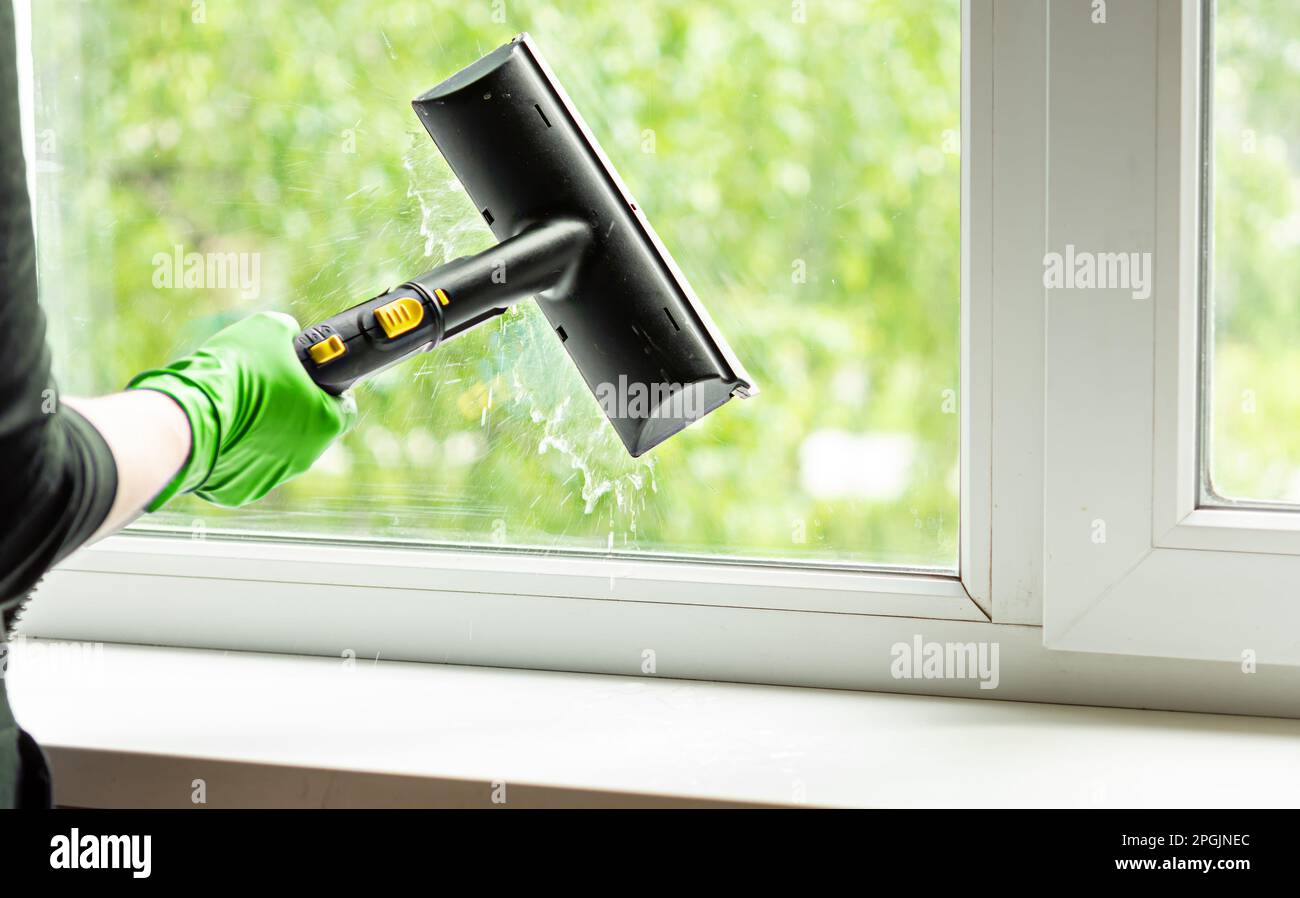 femme lave les fenêtres d'une maison avec un générateur de vapeur. Nettoyer la maison au printemps. Nettoyage de la maison. mise au point sélective. Banque D'Images