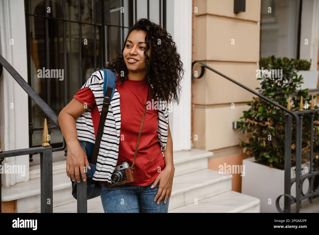 Jeune femme noire souriant en se tenant debout près du bâtiment à l'extérieur Banque D'Images