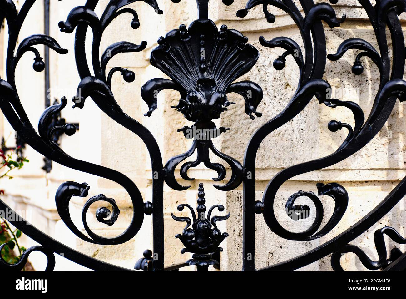 clôture en fer forgé noir au-dessus de la base et du seuil en pierre beige. éléments décoratifs en acier forgé entre les tiges verticales en acier. arrière-plan en pierre flou et doux. Banque D'Images