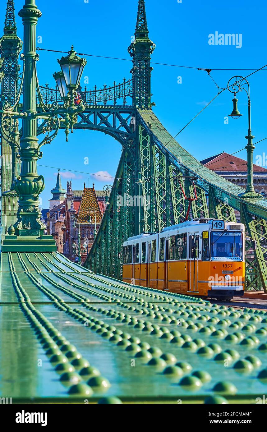 Le tramway jaune vintage, qui monte sur le pont de la liberté contre les constructions en métal vert vif, Budapest, Hongrie Banque D'Images